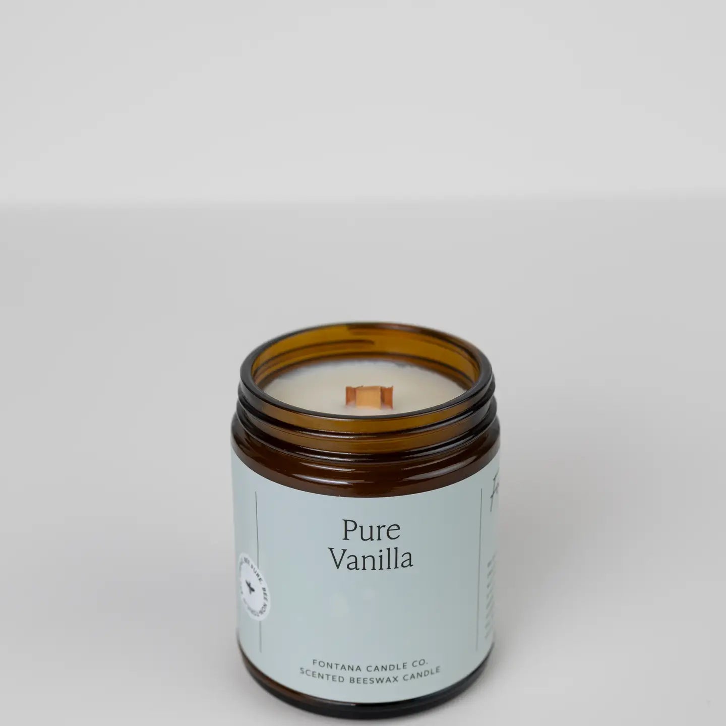A beige jar candle labeled 'PURE VANILLA' with a white label and a small visible wick, on a white background.