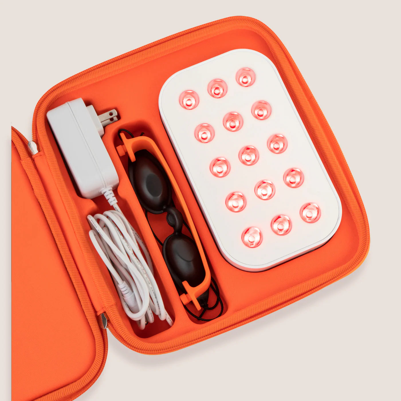 Portable LED device with accessories in an orange case on a light gray background