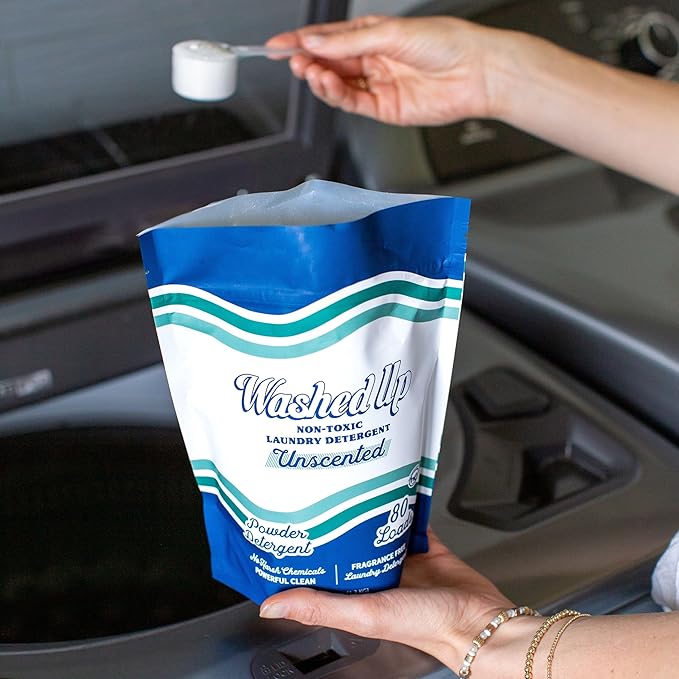 A person holds a bag of laundry detergent, ready to use it for washing clothes.