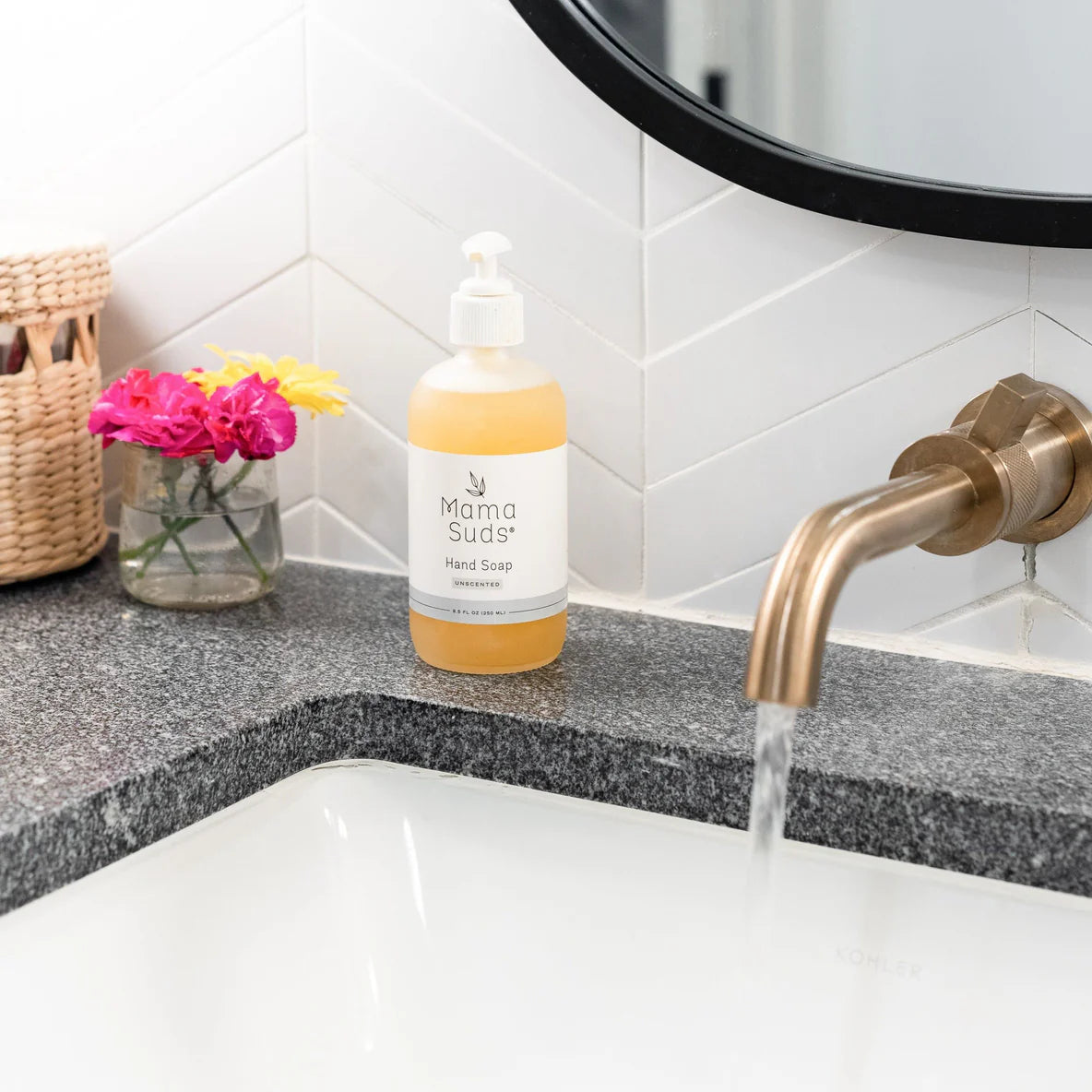 Hand soap bottle on a bathroom counter with sink and faucet.