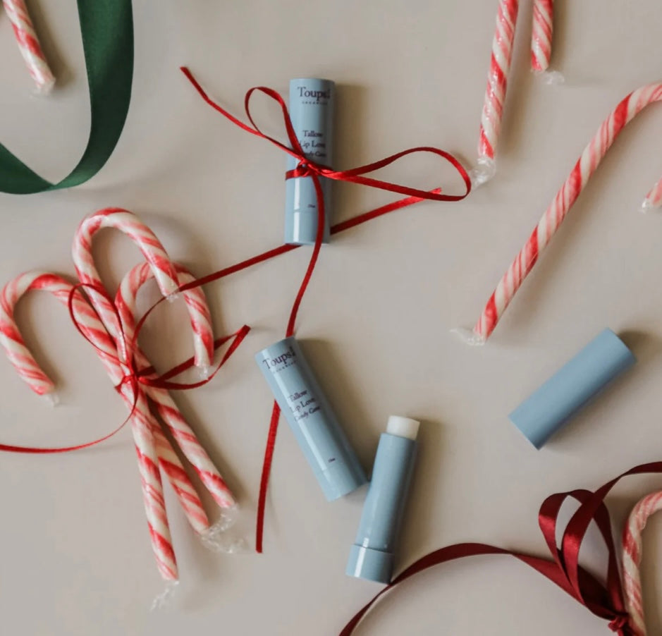 Lip balm tubes with ribbons and candy canes on a light background