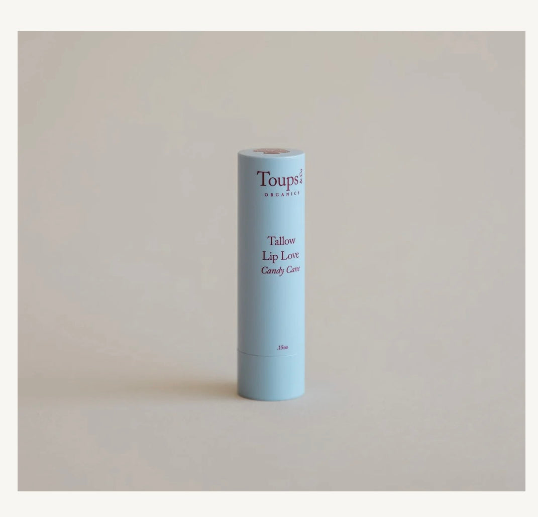 Toupsi Tallow Lip Love Candy Cane lip balm tube on a beige background