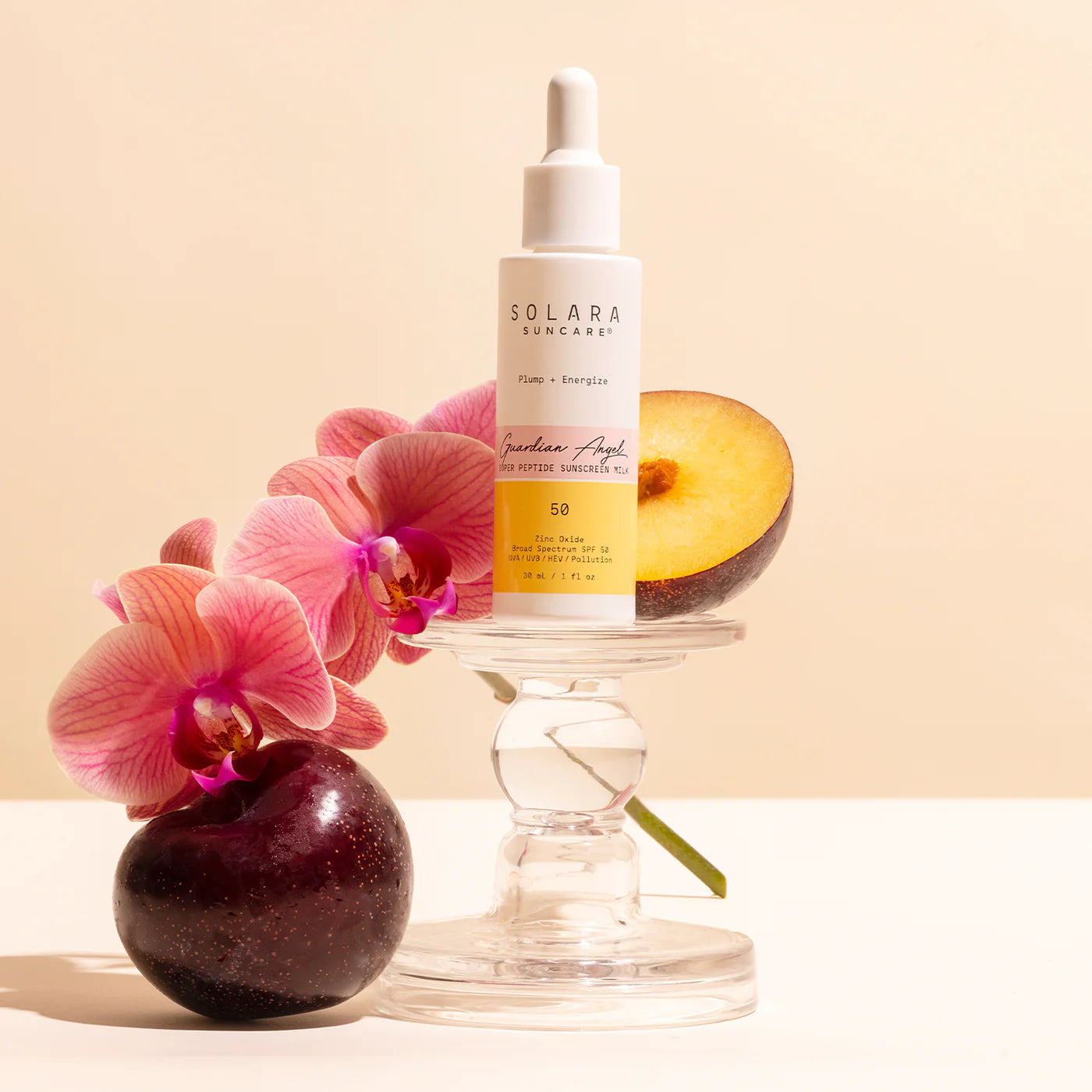 A sunscreen dropper bottle on a glass stand, surrounded by vibrant pink orchids and ripe plums, against a soft beige background. Elegant and fresh.