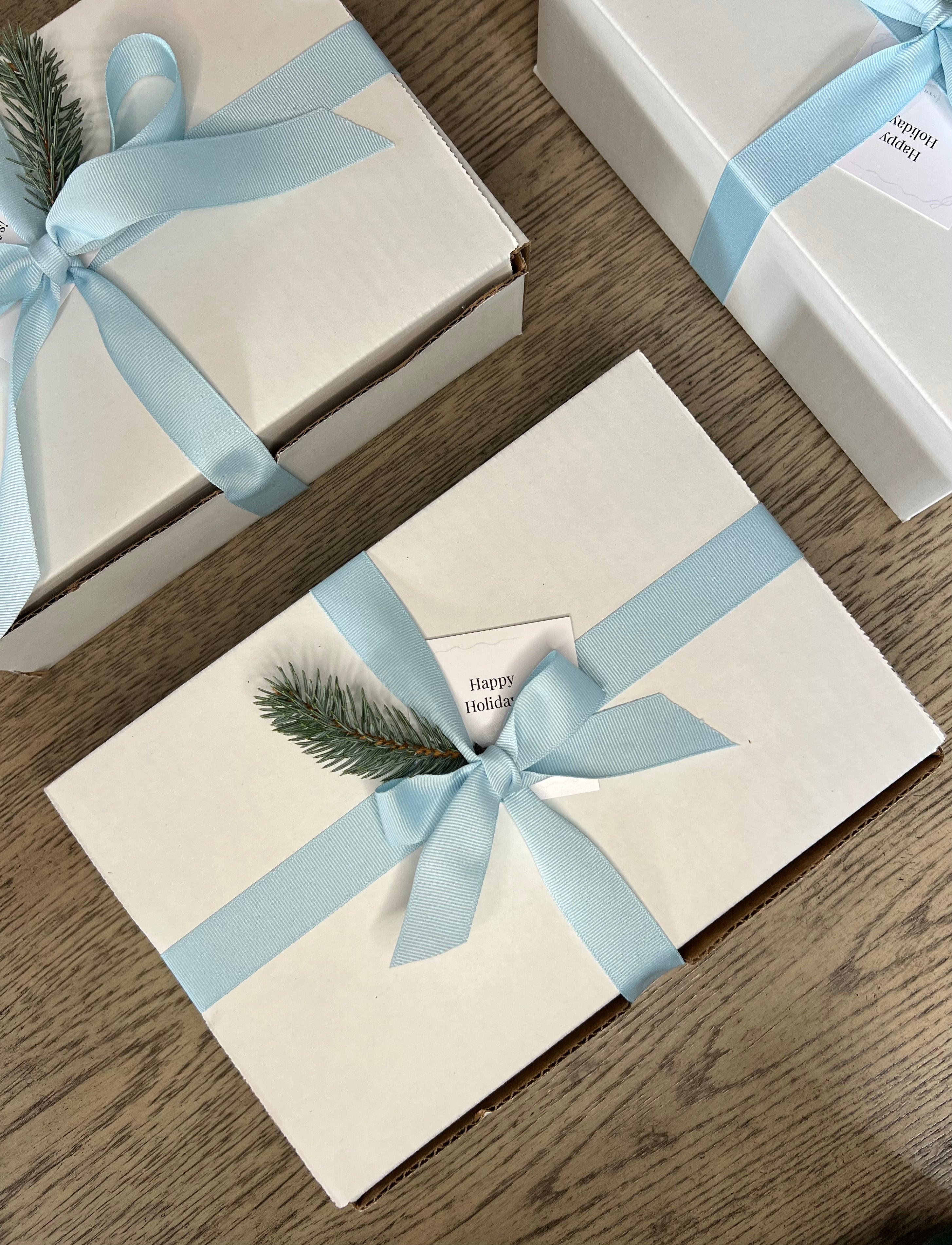 Three gift boxes with light blue ribbons on a wooden surface