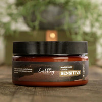 Earthley magnesium lotion jar with a black lid on a wooden surface