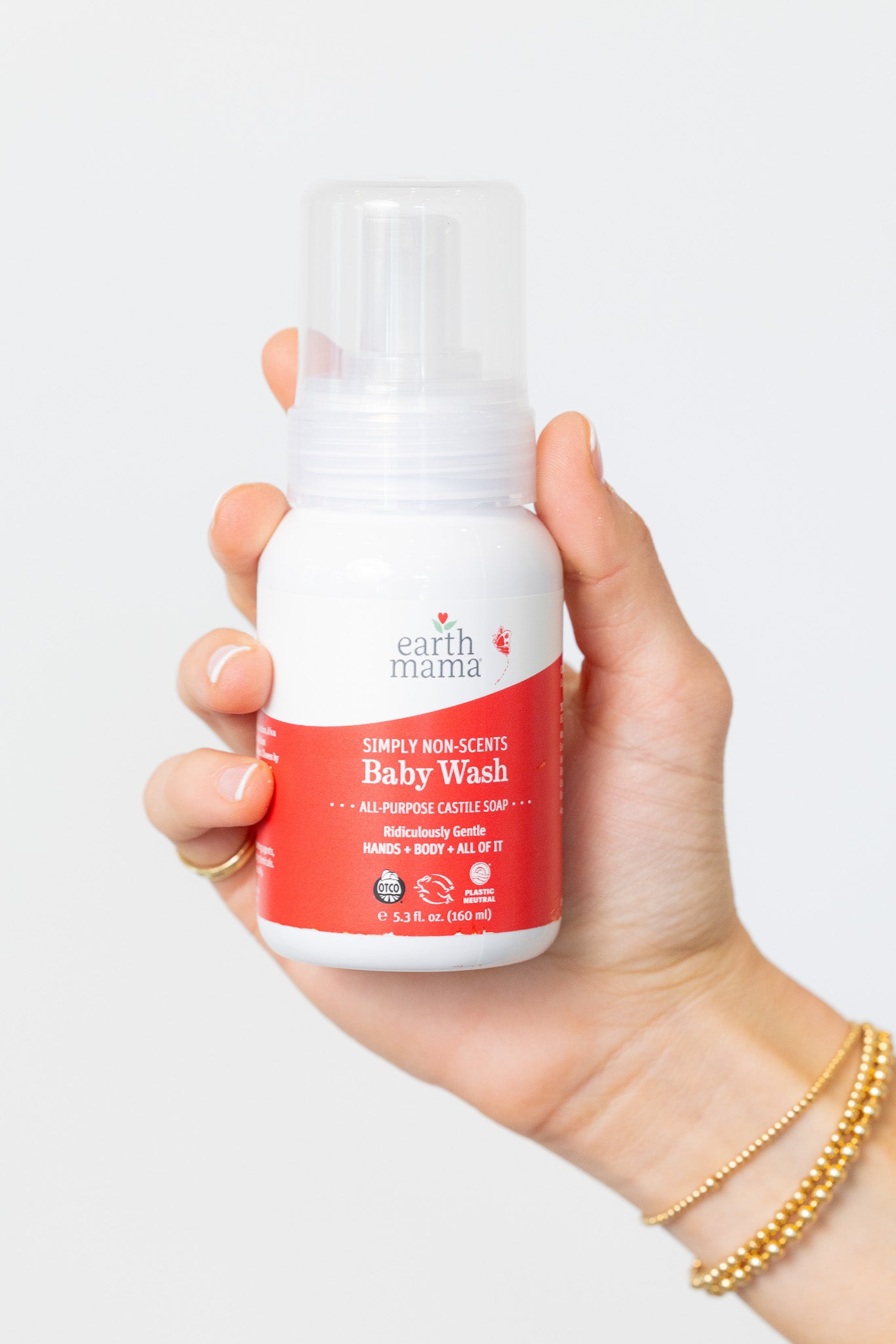 Hand holding a bottle of Earth Mama Baby Wash against a white background
