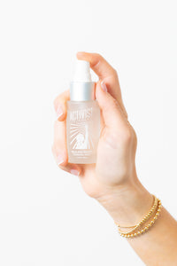 A hand holding a spray bottle of Healing Water Toning Mist with a white label.