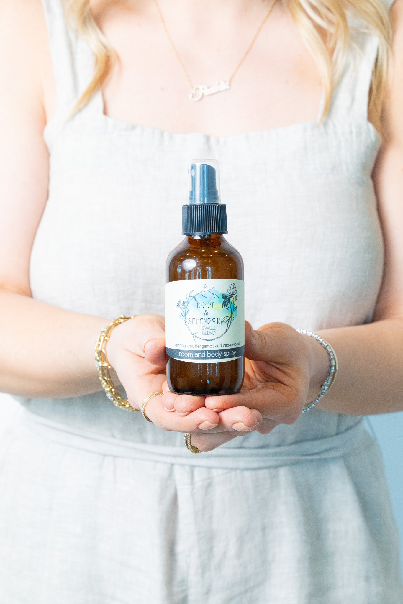 Person holding a bottle of 'Herbal Academy' spray with a white background