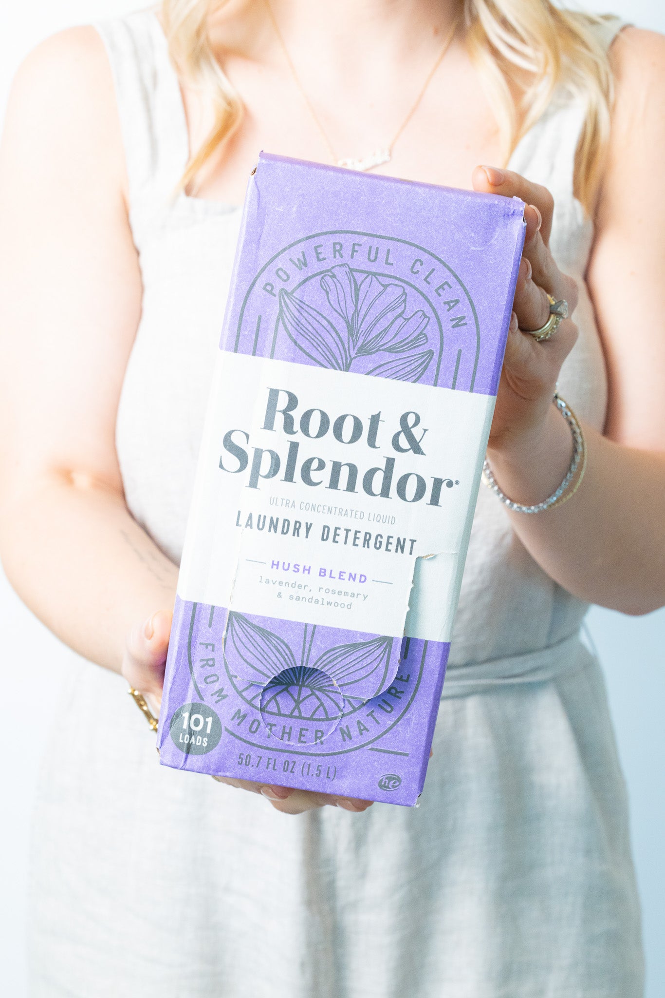 Two packages of Root and Splendor laundry detergent in a basket with laundry clothes. One package is labeled 'Hush Blend' with purple and gray design, and the other is 'Fresh & Clear' with a yellow and green design.