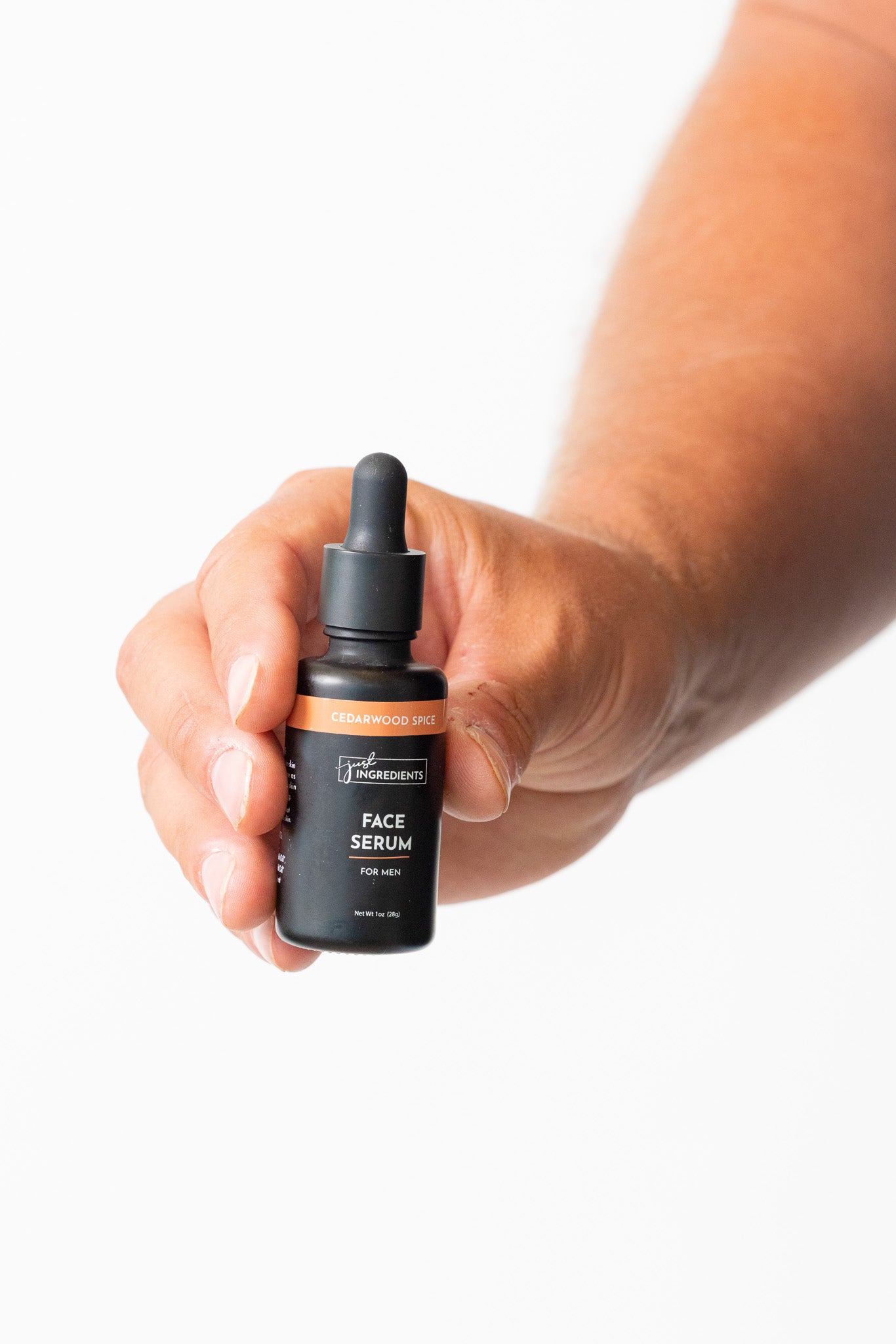 Hand holding a bottle of face serum with a dropper on a white background