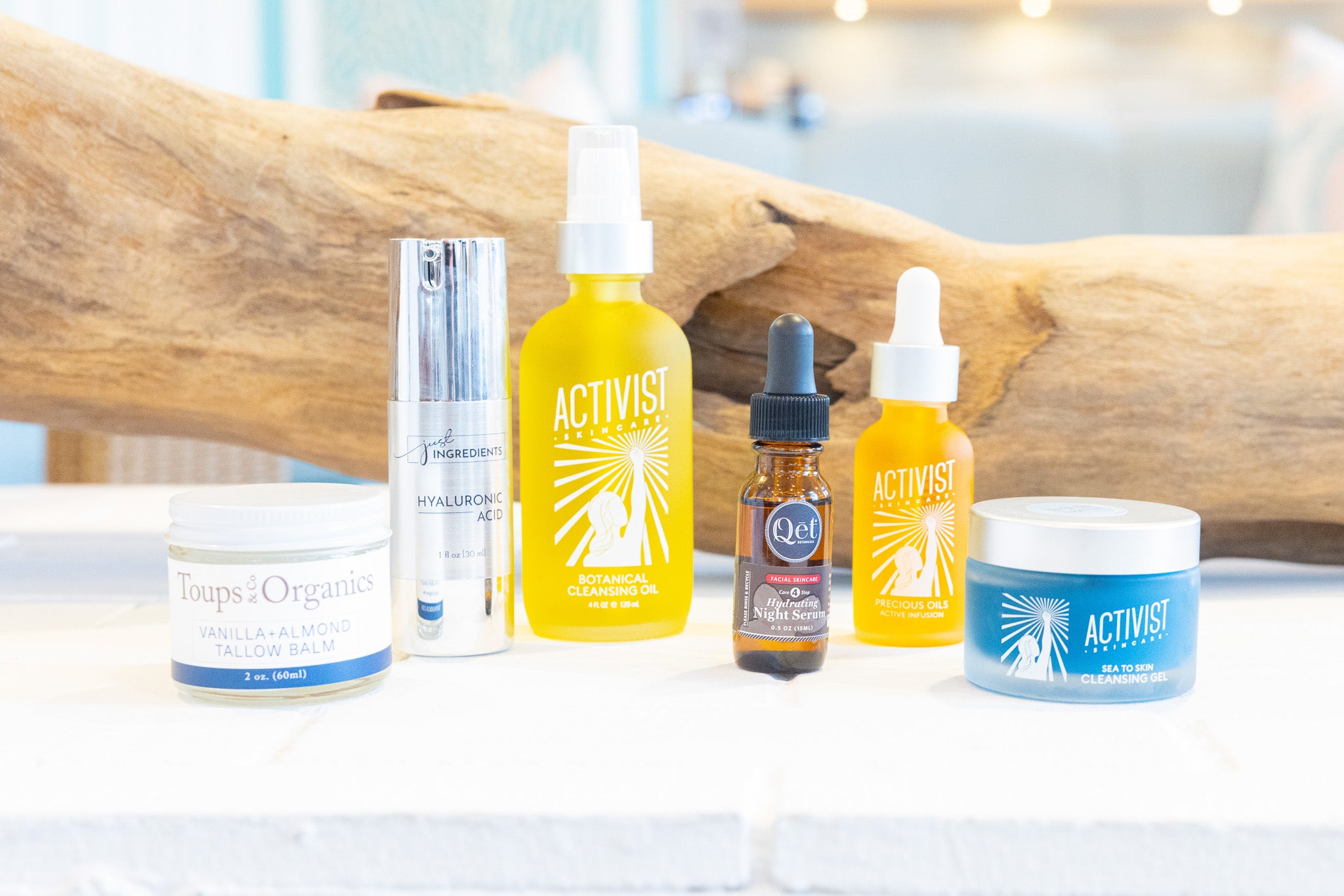 Collection of Activist skincare products on a white surface with a wooden background
