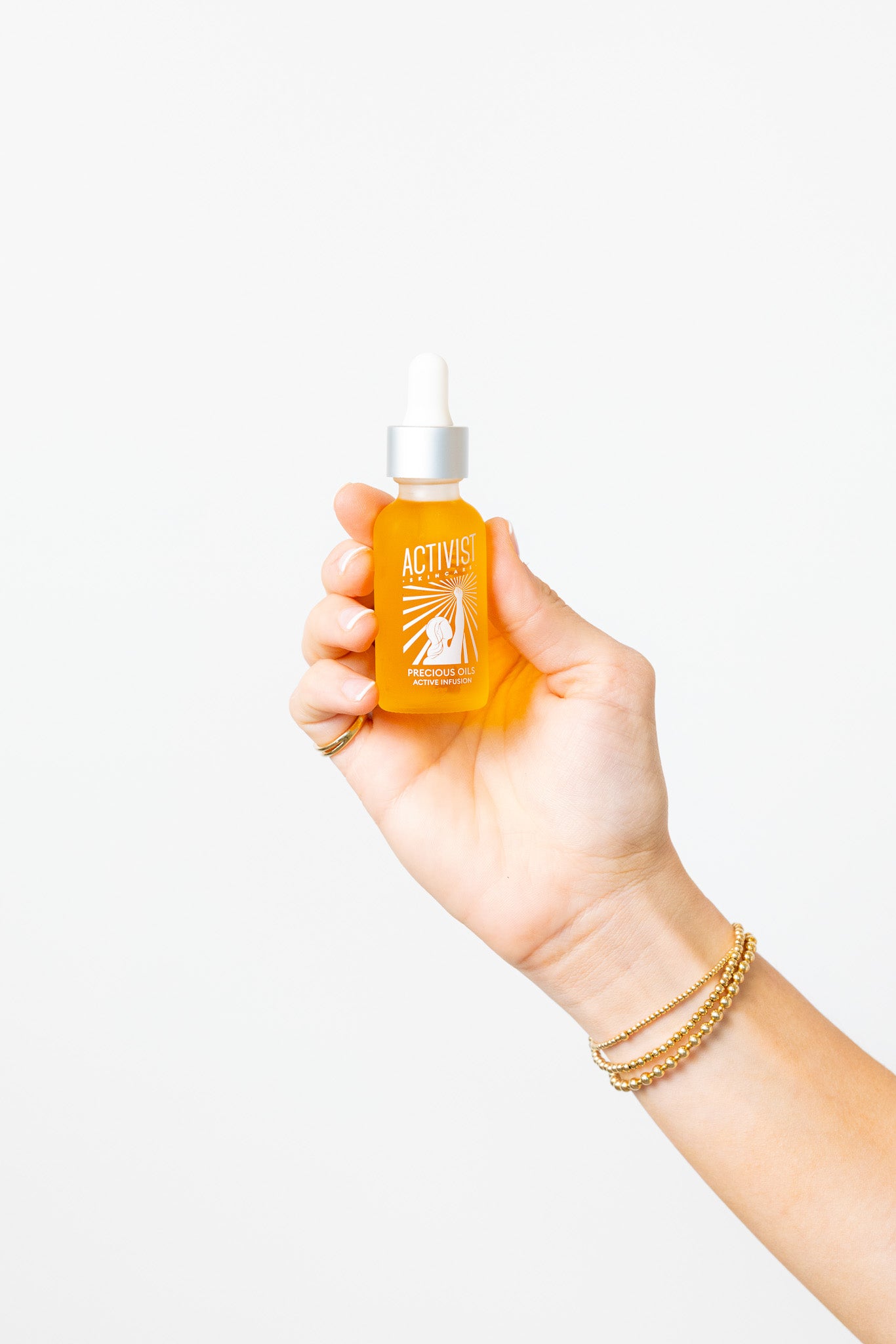 Hand holding a yellow liquid dropper bottle against a white background