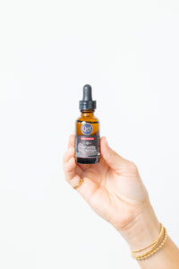 Hand holding a bottle of serum with a white background