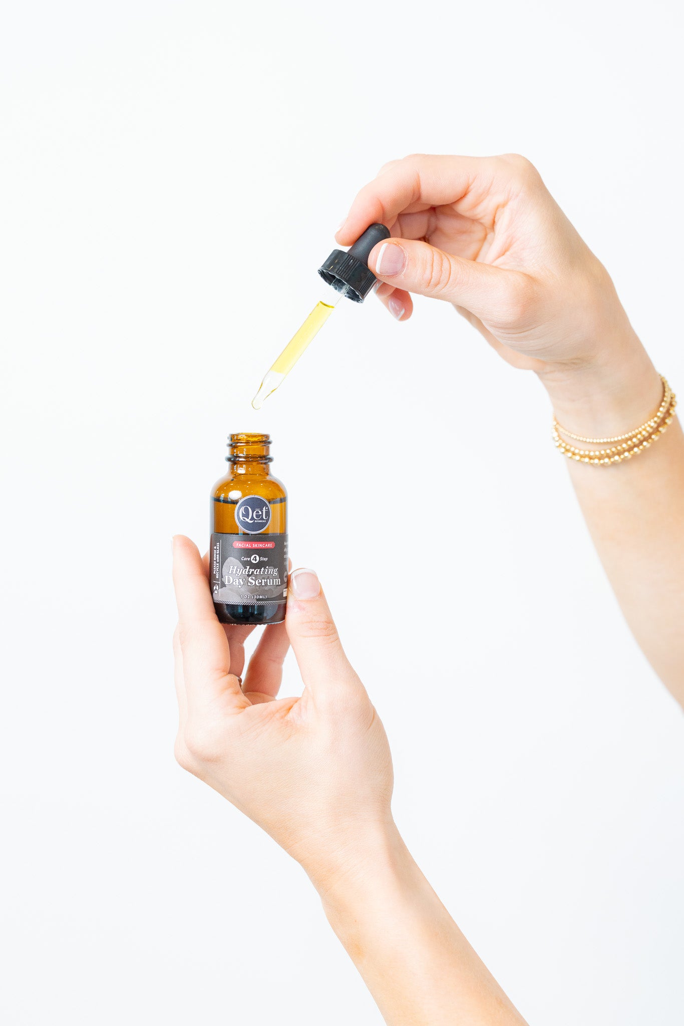 Person holding a bottle of serum with a dropper, on a white background
