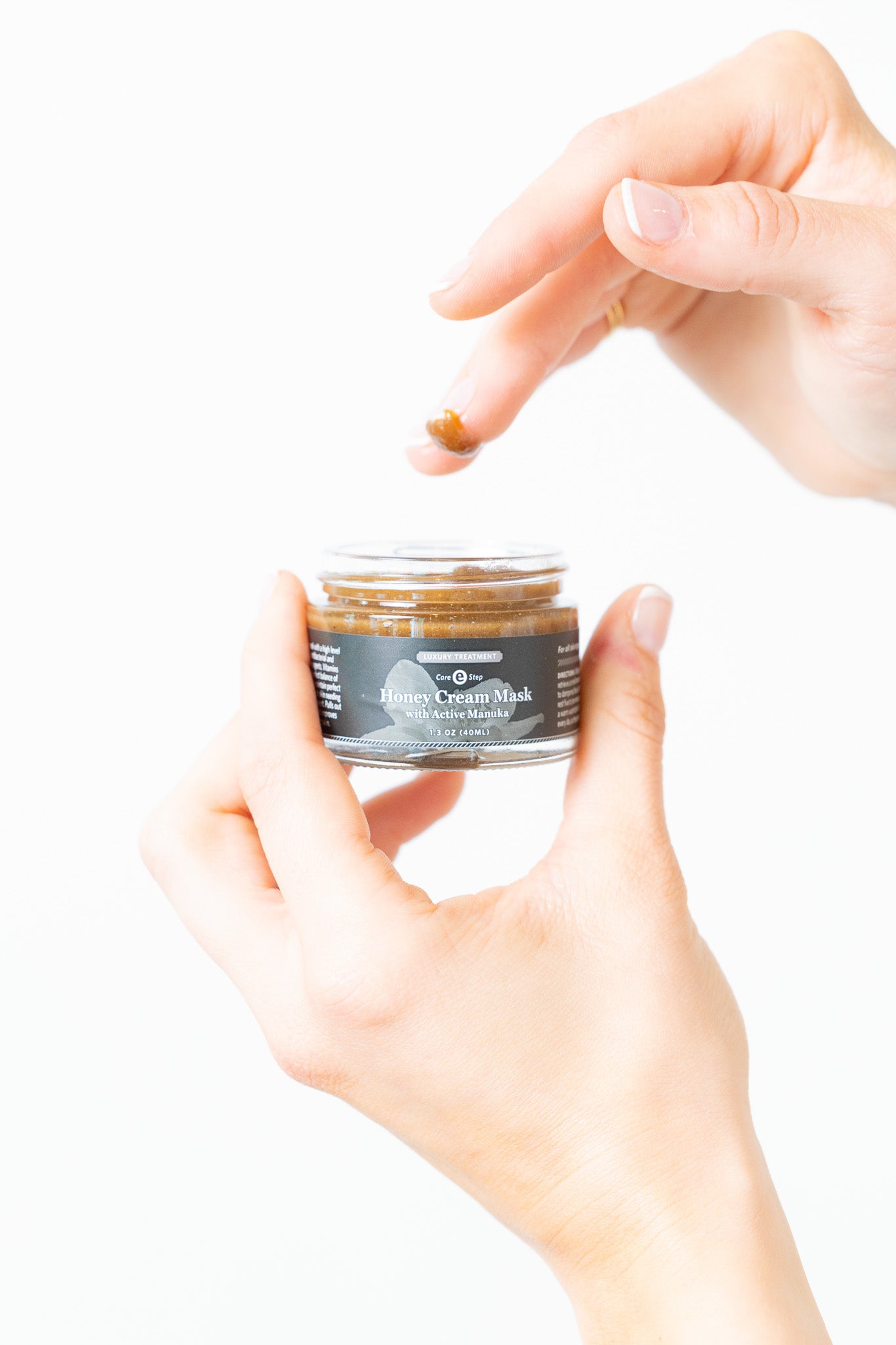 Hand holding a jar of hair cream with a white background