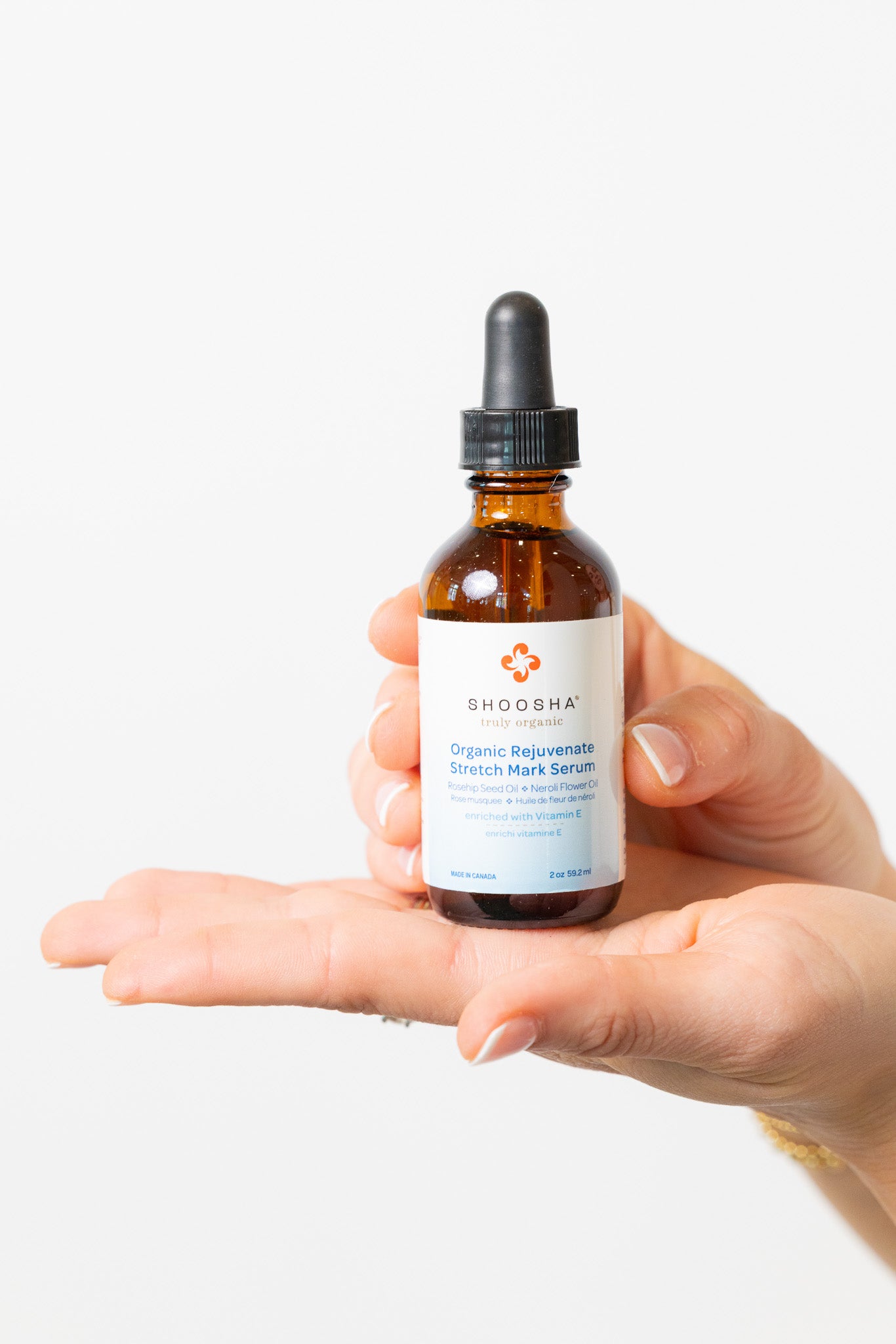 Hand holding a bottle of Shousha hair serum against a white background