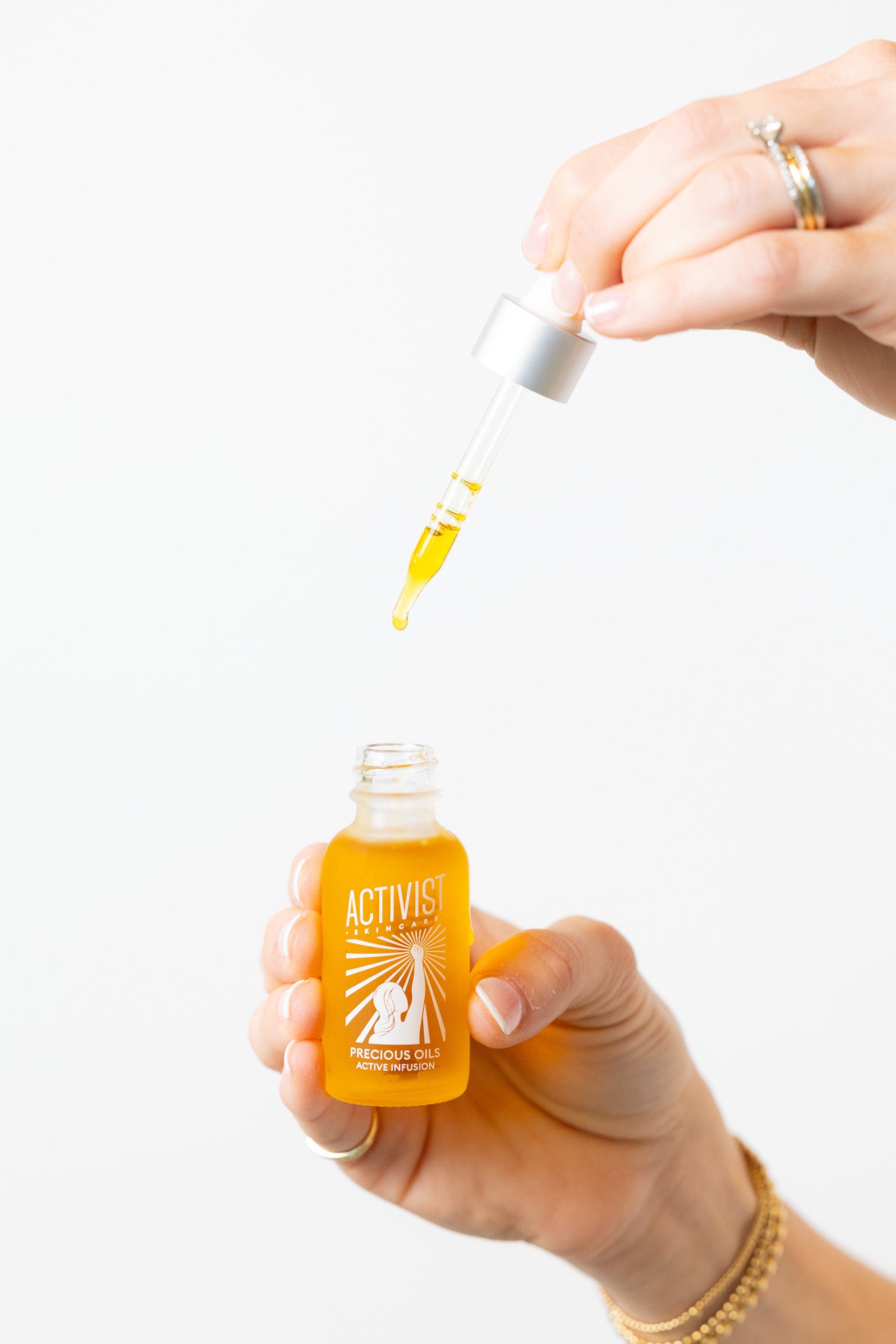 Hand holding a small avtivist bottle with a dropper, filled with yellow liquid.