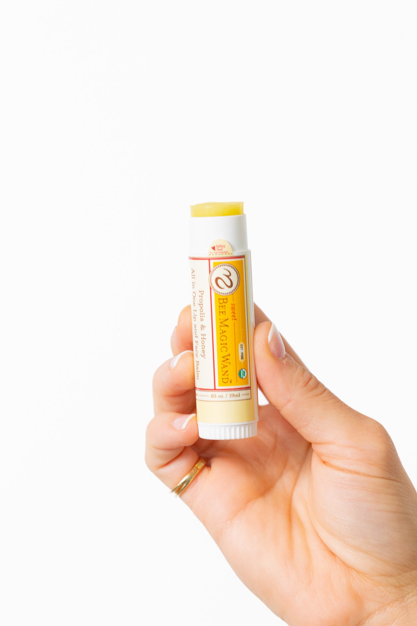 Hand holding a lip balm stick with a white background