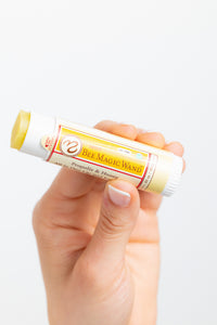 Hand holding a tube of 'Bee Magic Wand' product on a white background