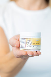 Person holding a jar of All in One Healing Skin Cream with a blurred background