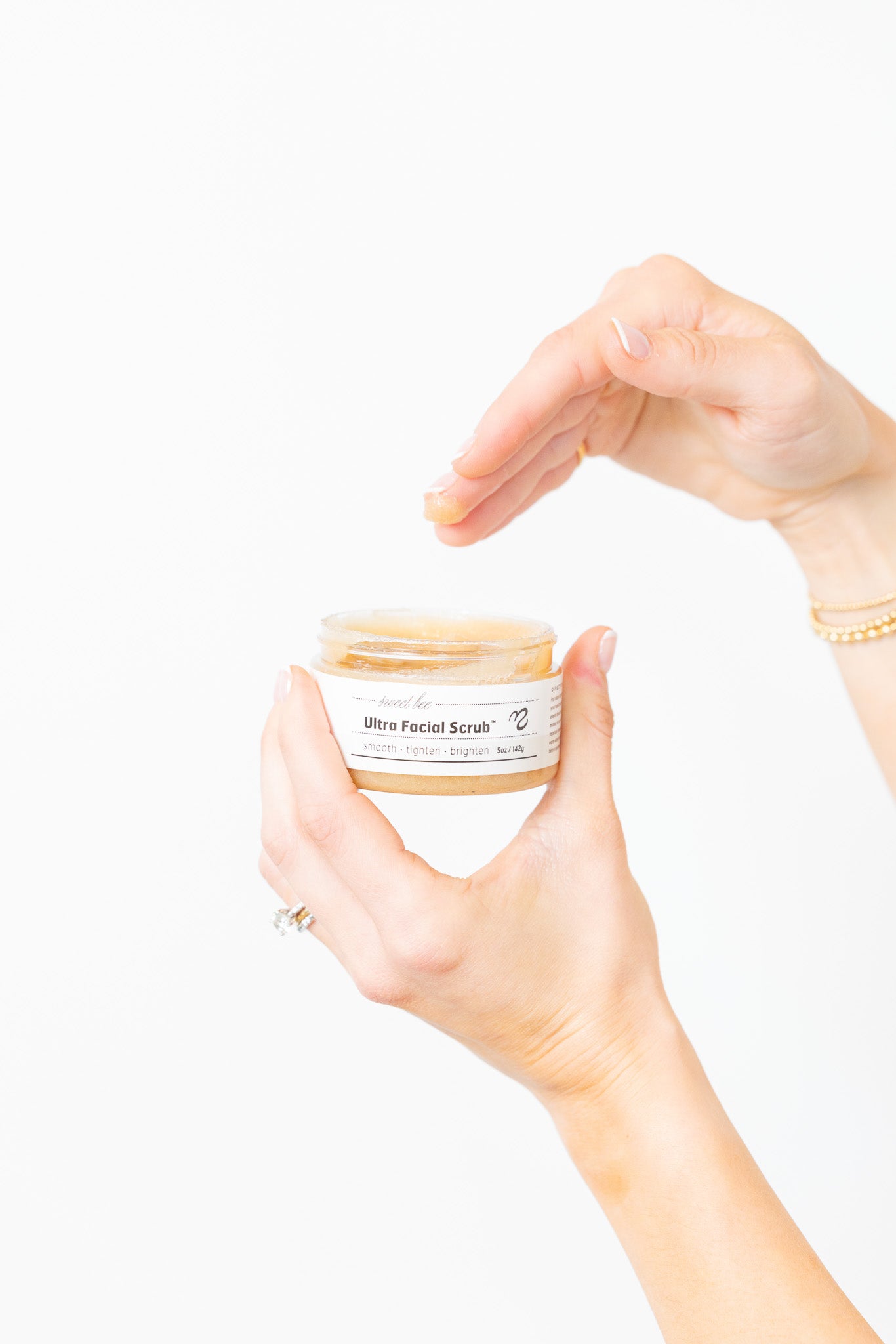 Person holding a jar of Ultra Facial Scrub with a plain background