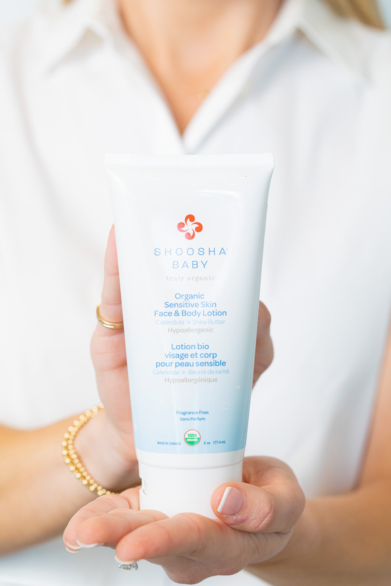 Person holding a bottle of Gathia Baby lotion with a white background