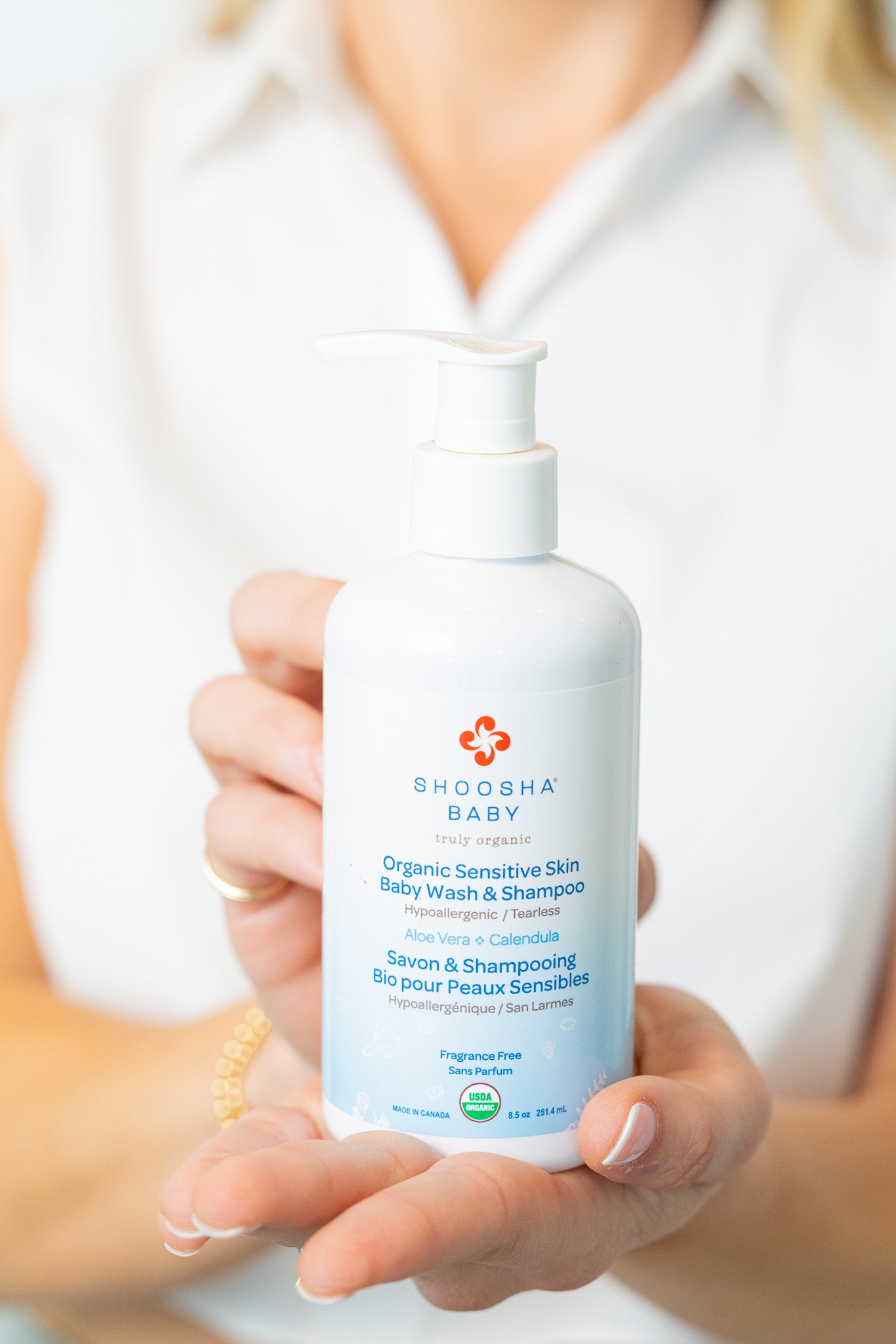 Person holding a bottle of Shouha Baby organic shampoo and conditioner.