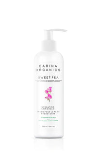 White bottle of Carina Organics Sweet Pea Hydrating Skin Cream with pump. Features floral graphic and minimalistic design, conveying freshness and purity.