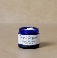 A blue jar labeled 'Toups & Organics Frankincense Face Balm' set against a neutral background.