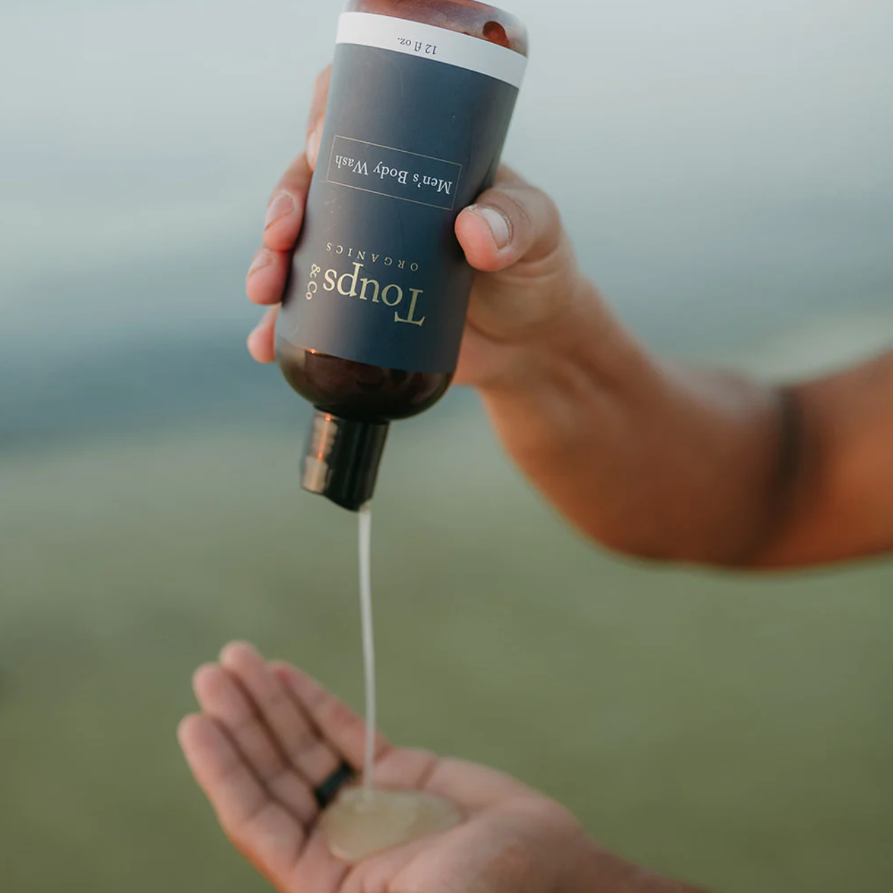 A dark bottle tipped, pouring a smooth body wash.