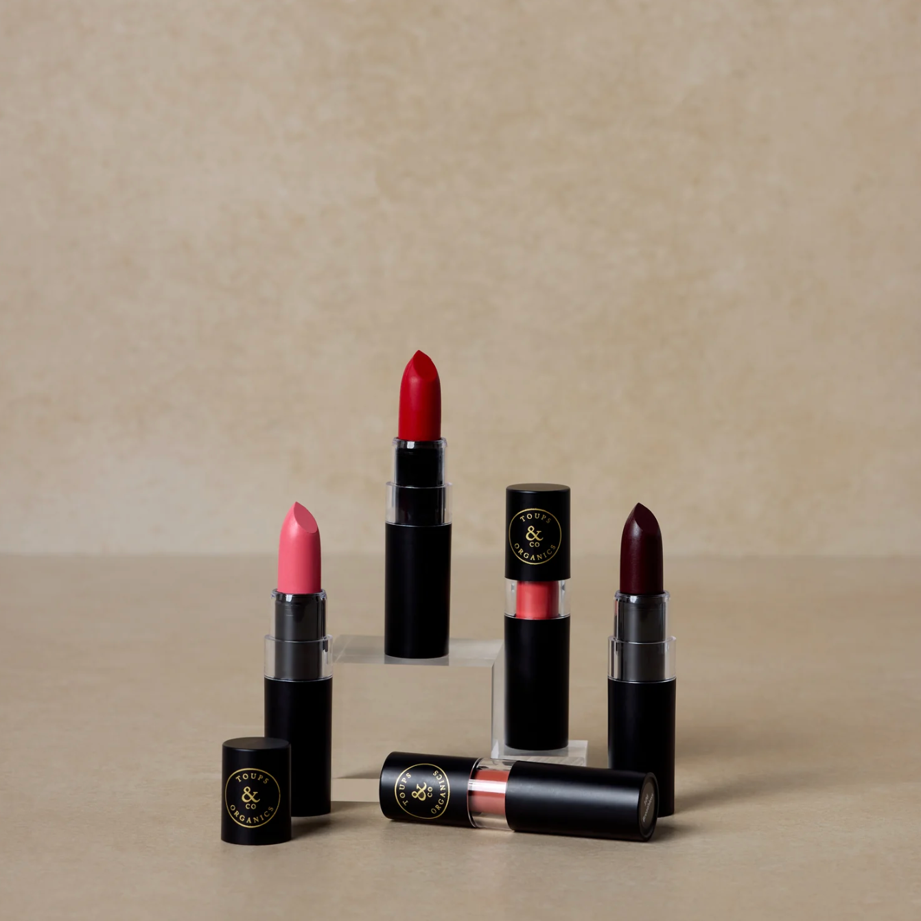 A collection of Nourishing Lipsticks in various shades, displayed in individual tubes and a few swatches on a surface with a neutral background.