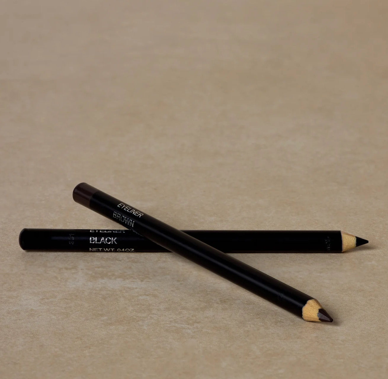 A pencil eyeliner in black color with a cap, displayed on a textured beige surface.