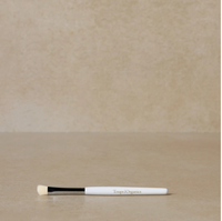 An eye shadow brush with a white handle and black bristles, labeled with the brand 'Toups & Co'.
