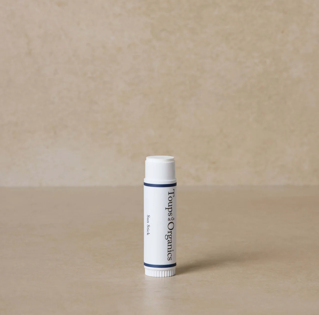 White lip balm tube with black text on a beige background