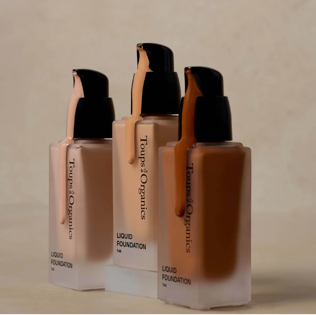 Three bottles of Tones & Origins liquid foundation on a beige background