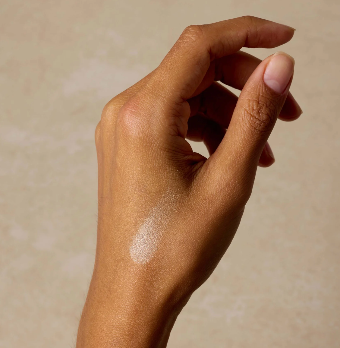Hand with a small amount of white powder on a beige background
