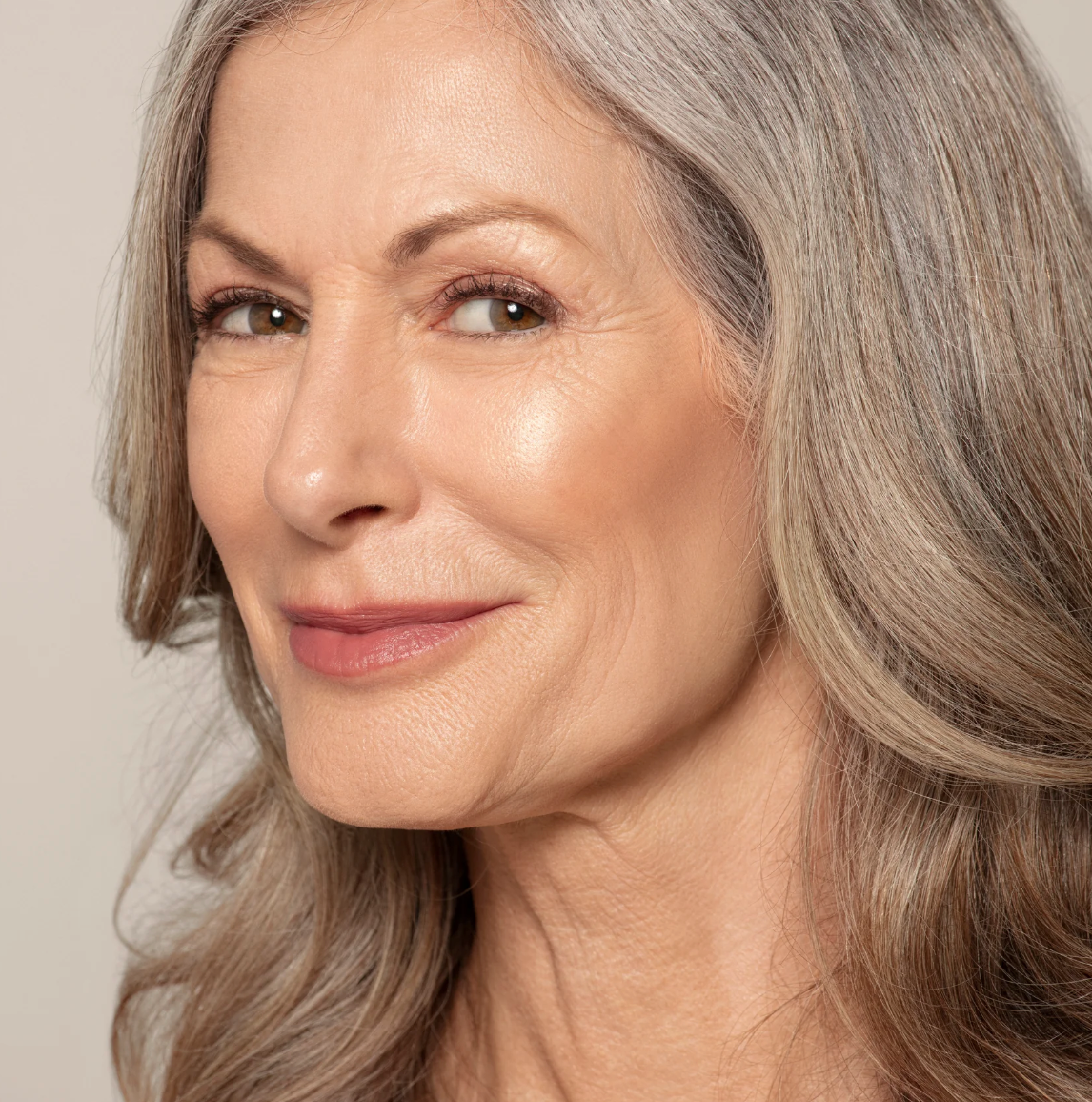 Close-up of a woman with gray hair against a plain background