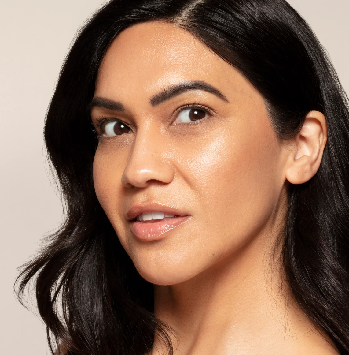 Close-up of a woman with dark hair and neutral background