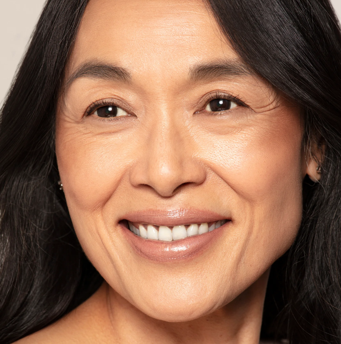 Close-up of a woman with a warm smile against a neutral background