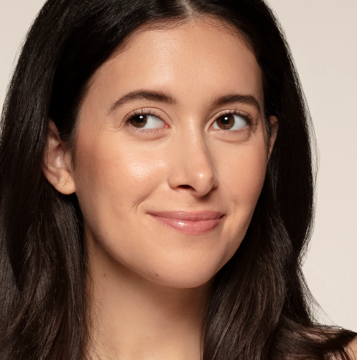 Close-up of a woman with long dark hair against a neutral background