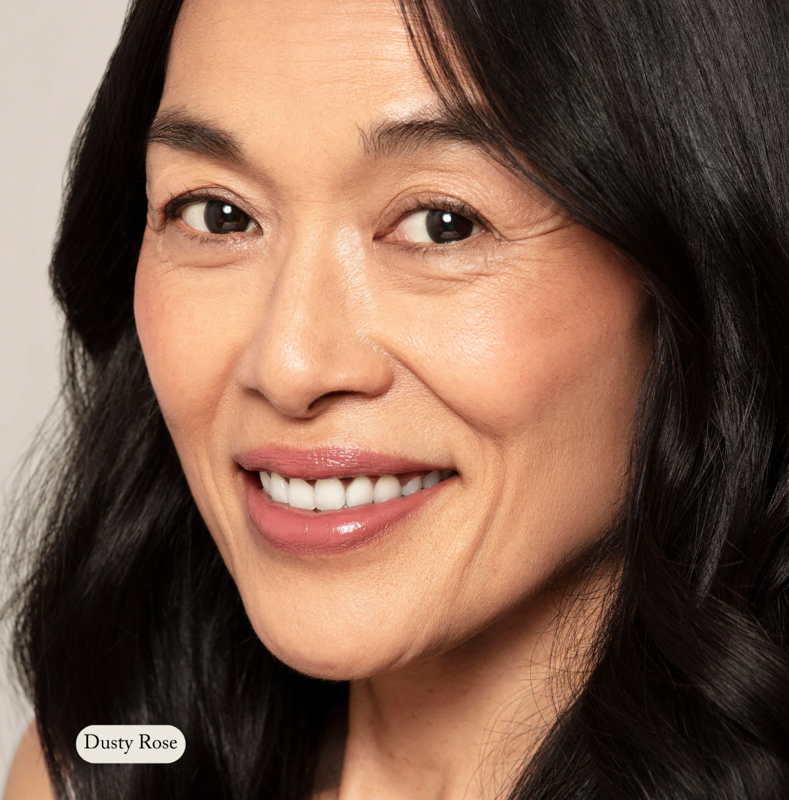 Close-up of a woman with dark hair and a soft smile, wearing a light makeup look.