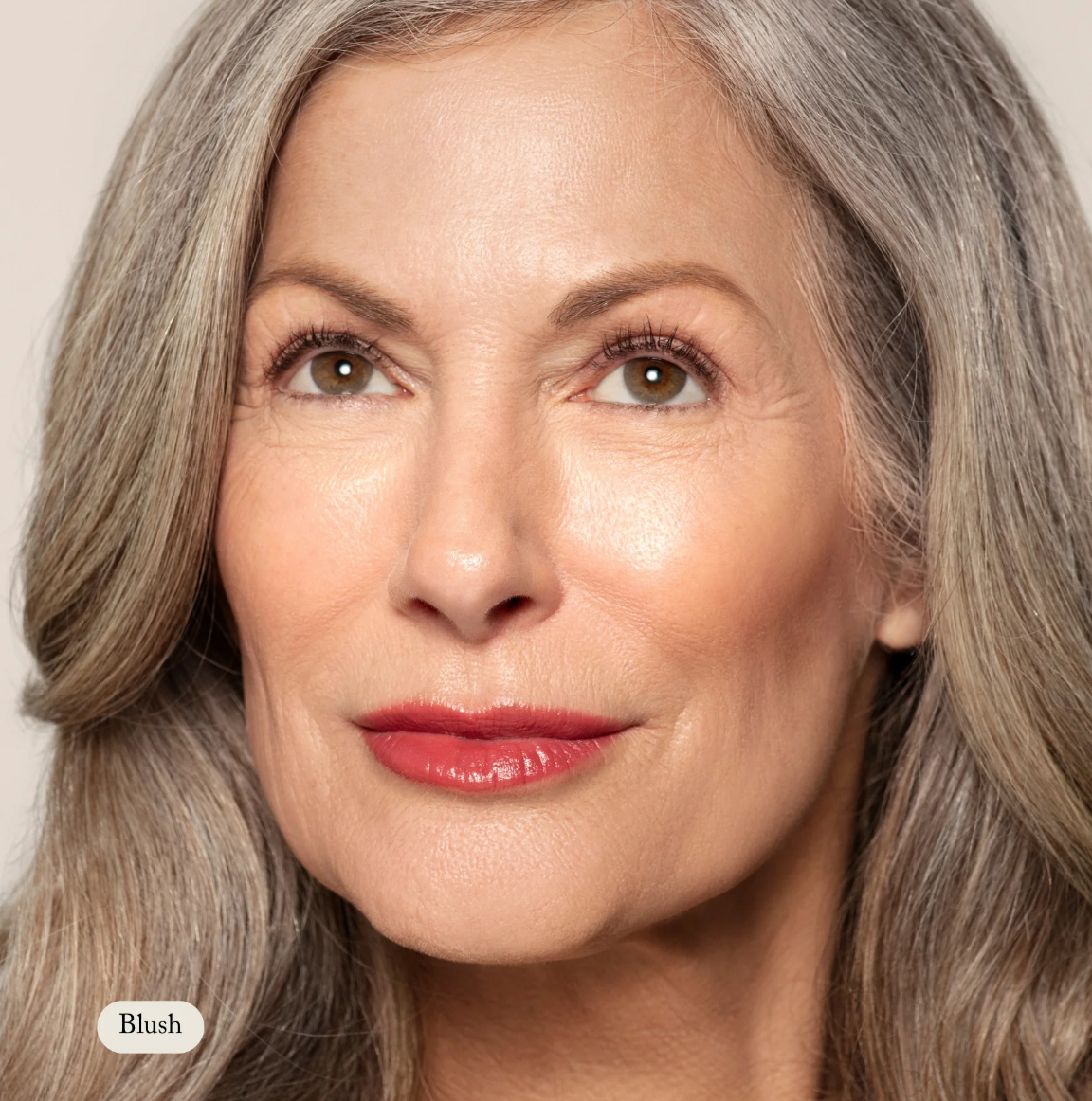 Close-up of a woman with gray hair and red lipstick against a neutral background