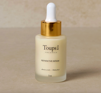 Toups & Co. reparative serum bottle with dropper on a beige background