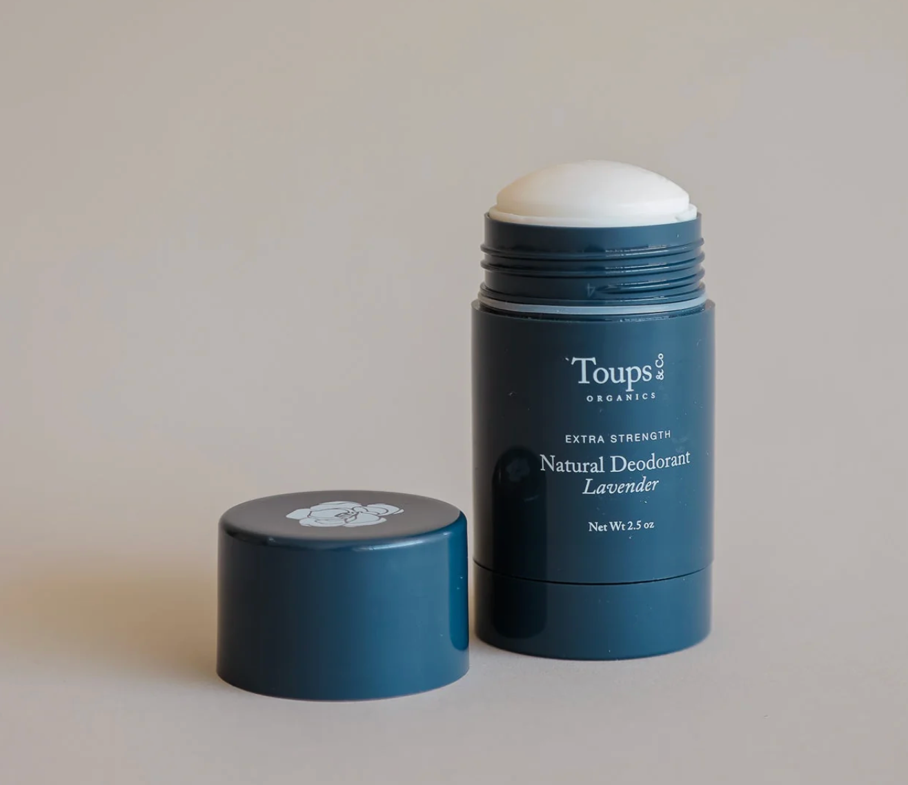 Blue natural deodorant stick with white cap on a beige background