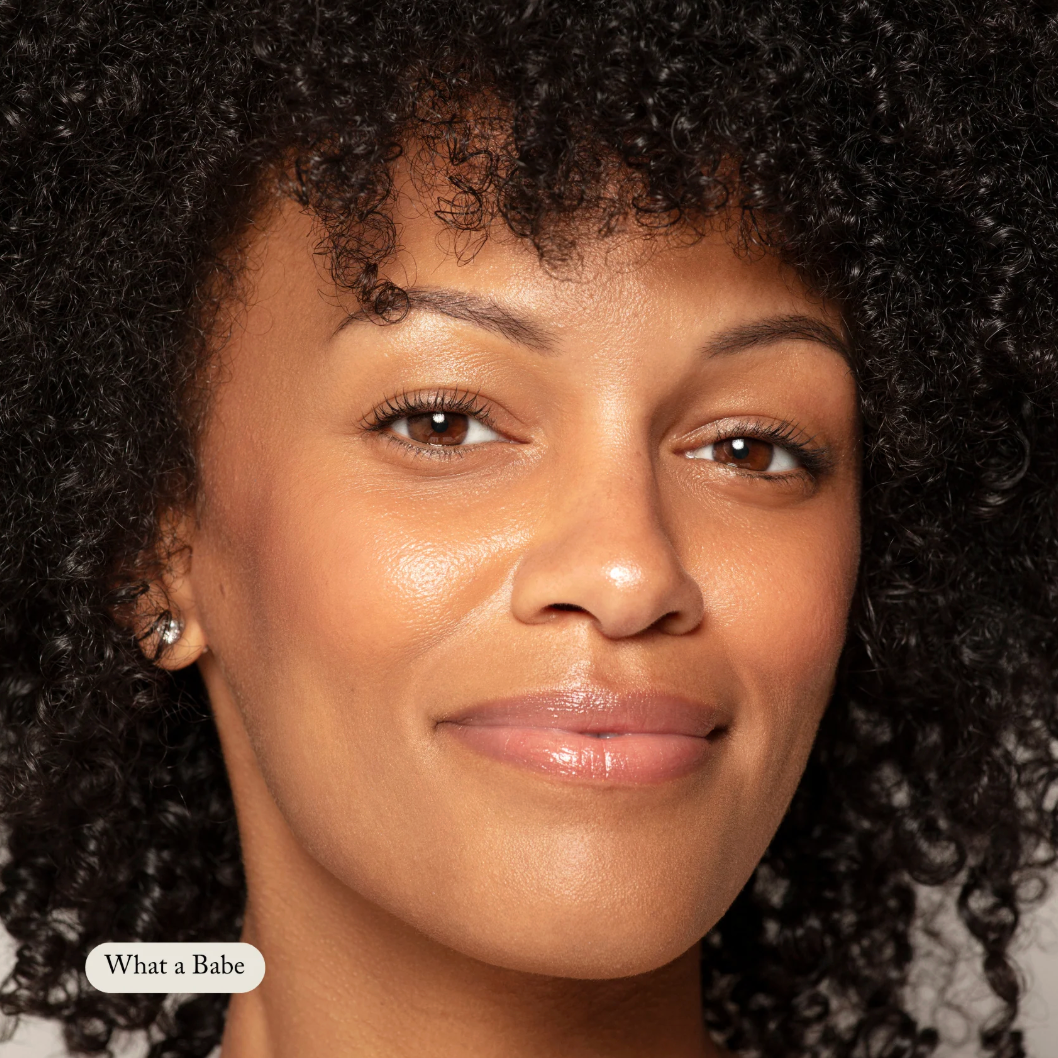 Close-up of a woman with curly hair, wearing earrings, with 'What a Babe' text at the bottom.