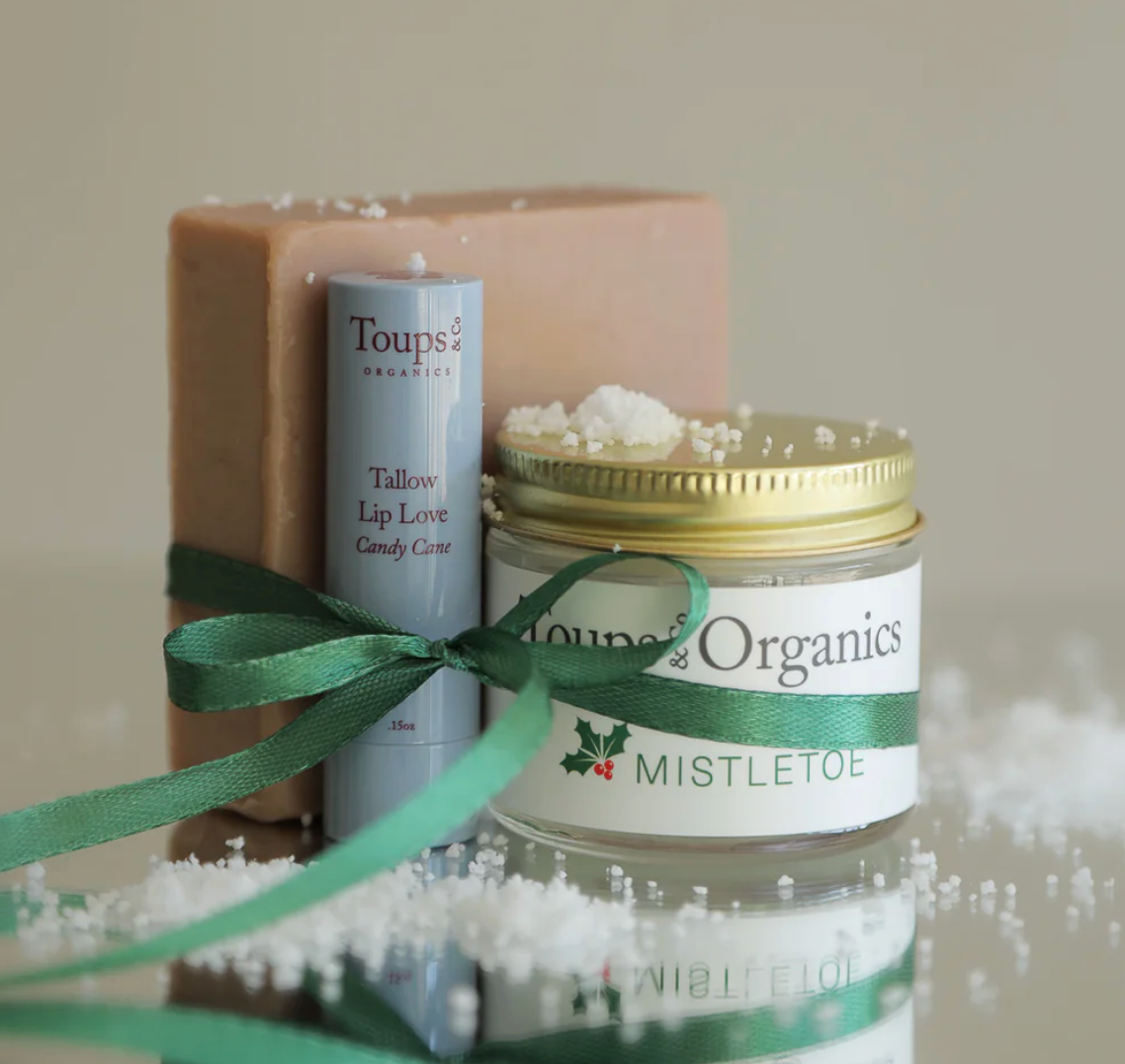 Cosmetic products with 'Toups Organics' branding on a neutral background