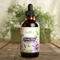 Bottle of Earthly Sleepy Time herbal supplement with a dropper on a wooden surface with plants in the background.