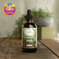 Bottle of Earthly Teeth Tamer supplement on a wooden surface with a blurred plant background.