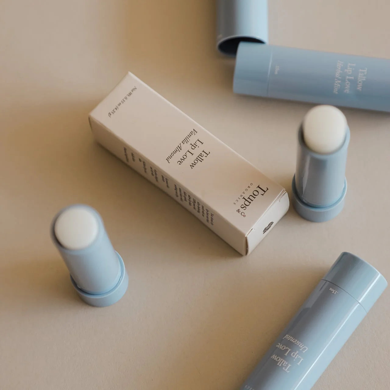 Cosmetic sticks and packaging on a beige surface