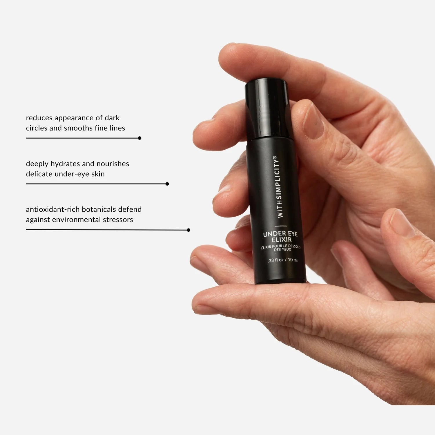 Hand holding a black skincare bottle with product benefits text on a white background